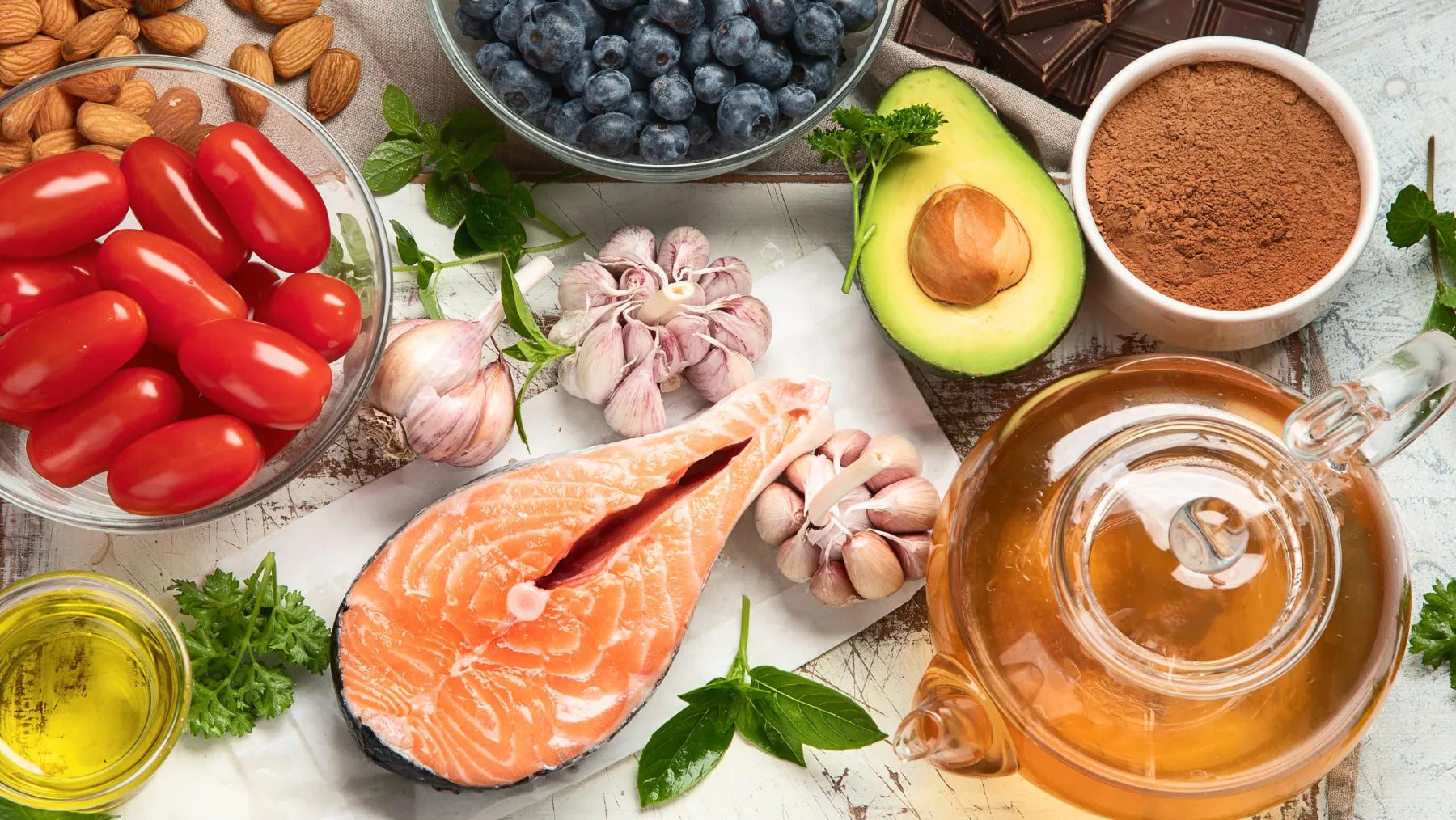 an assortment of foods including salmon, avocado, nuts, berries and chocolate