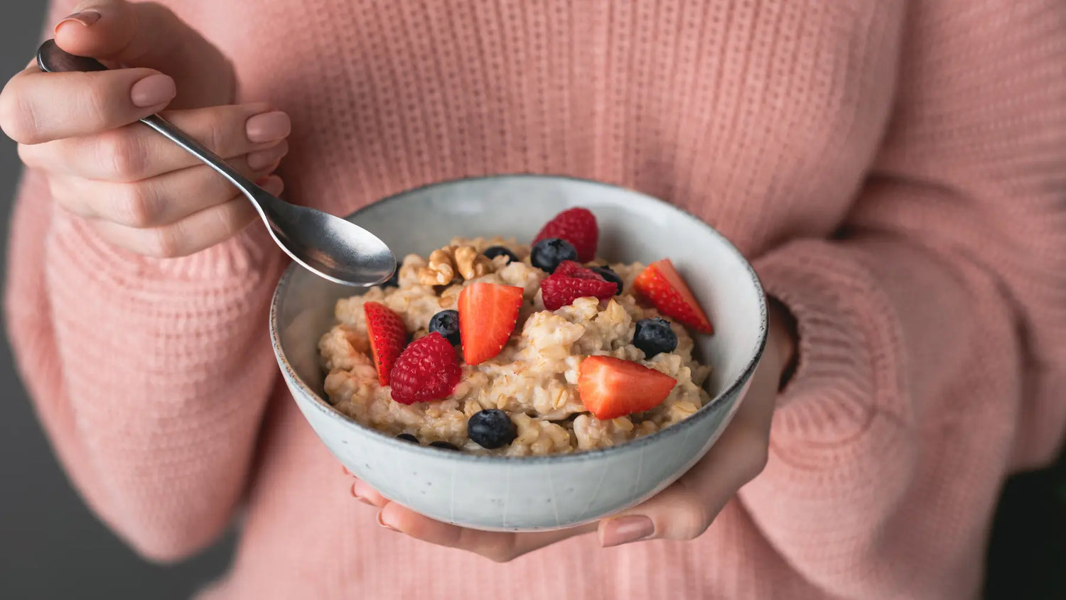 a person holding a bowl of overnight oats with berries