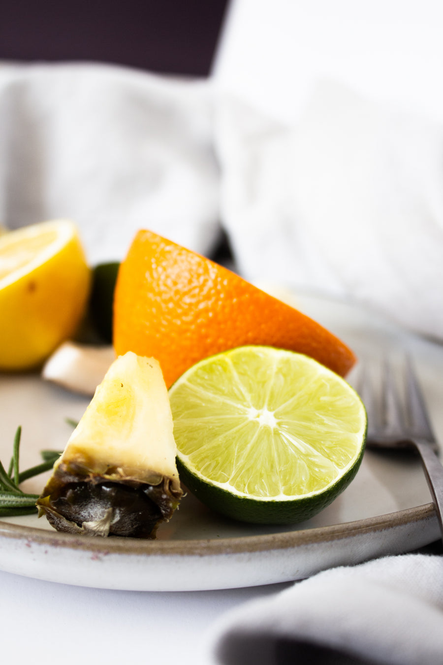 Fresh citrus wedges including lemon, orange, and lime with pineapple on a ceramic plate