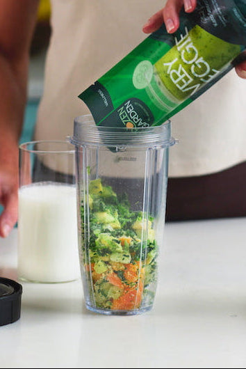 Woman pouring Frozen Garden's ready to blend frozen smoothie packs from her smoothie delivery into a blender.