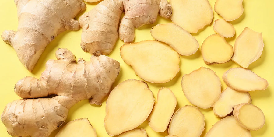 Whole and sliced fresh ginger root arranged on a bright yellow background.