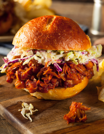 Bun with pulled jackfruit and coleslaw on a wooden cutting board