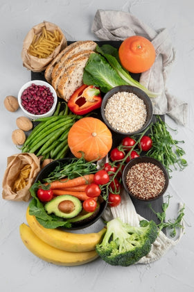 Assorted fruits, vegetables, grains, and other high fiber foods on a light gray surface