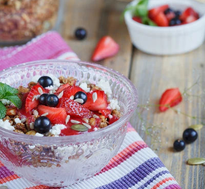 Bowl of cottage cheese with granola and fresh berries on a colorful napkin