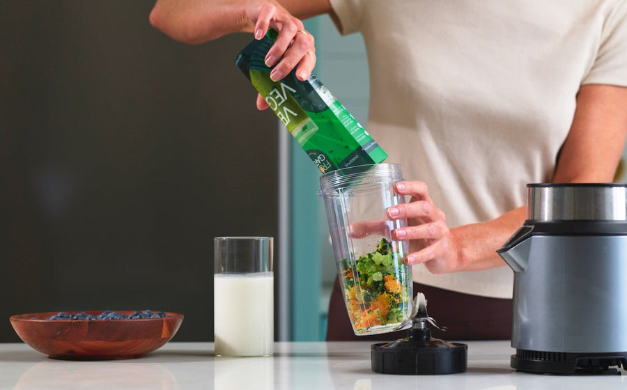 Pouring milk into a blender with Frozen Garden smoothie ingredients