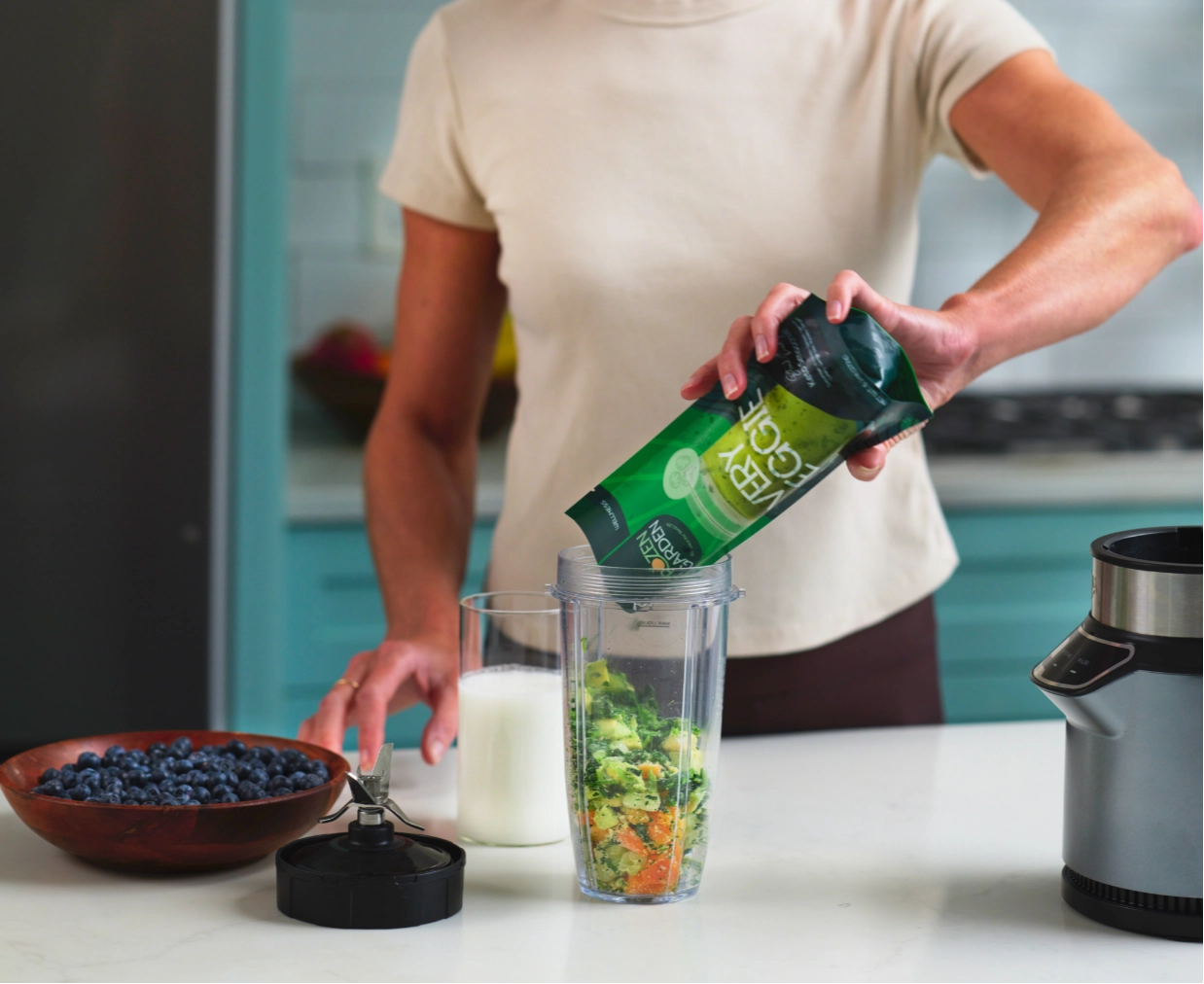 A woman pouring a convenient frozen smoothie pack into her blender.
