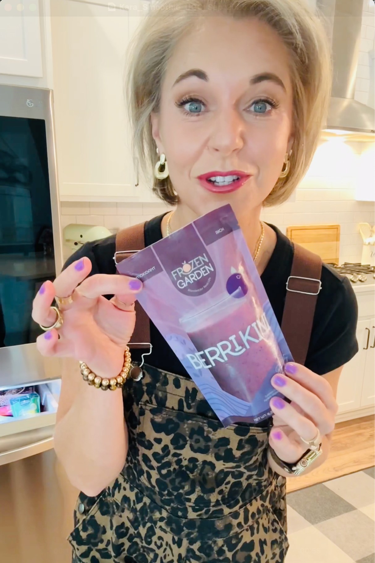 A woman holding up a Frozen Garden frozen smoothie pack from her smoothie delivery.