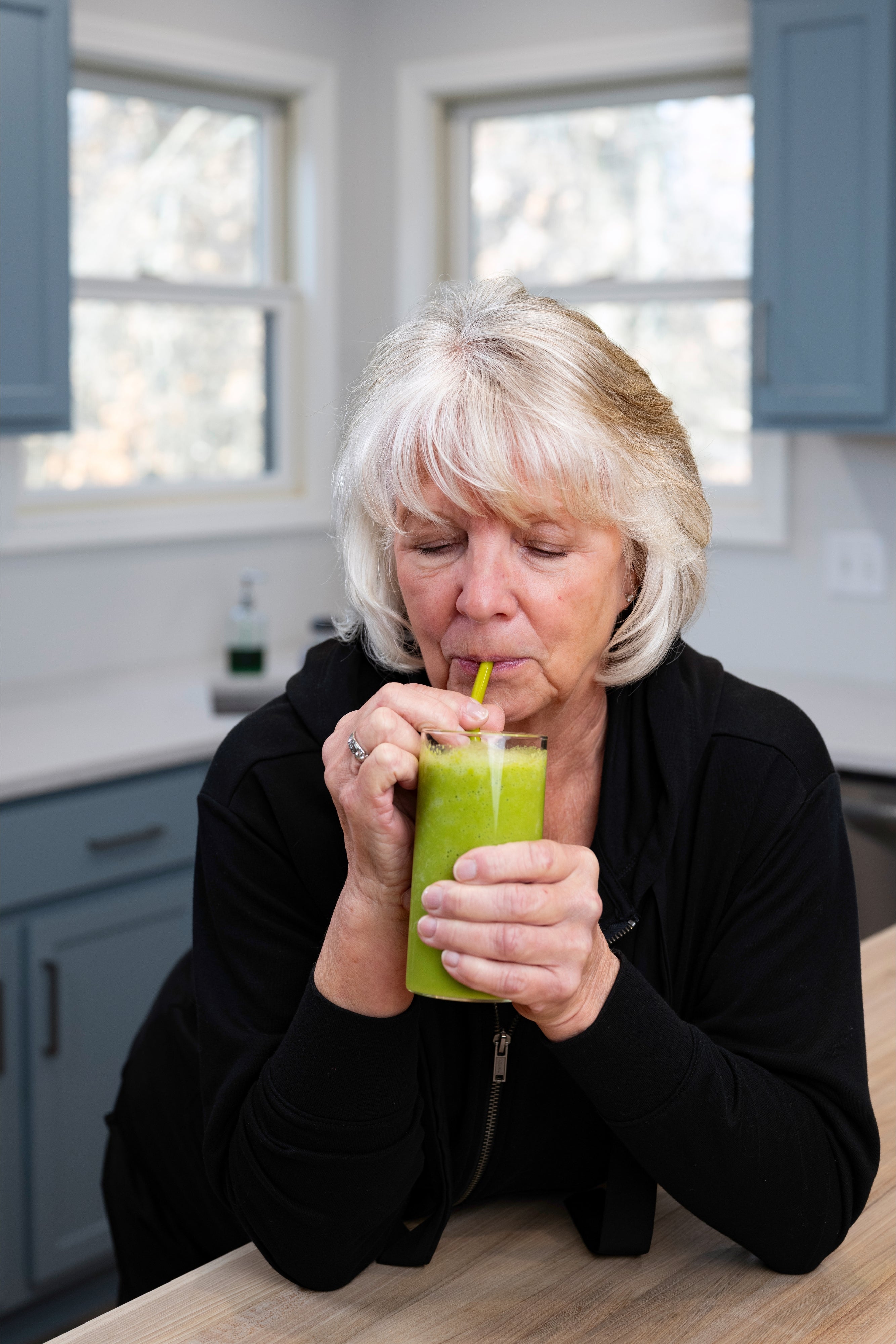 Woman drinking a green smoothie in a kitchen